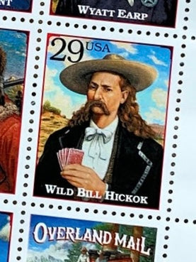 Close-up of a 29¢ U.S. postage stamp featuring Wild Bill Hickok from the 1994 Legends of the West series, showing him in a wide-brimmed hat holding playing cards.