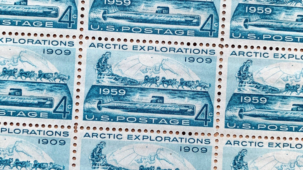 Close-up photo of Arctic Explorations stamp, U.S. postage stamp, 1959, Scott 1128, showing a dog sled team and the nuclear submarine USS Nautilus beneath the Arctic ice.